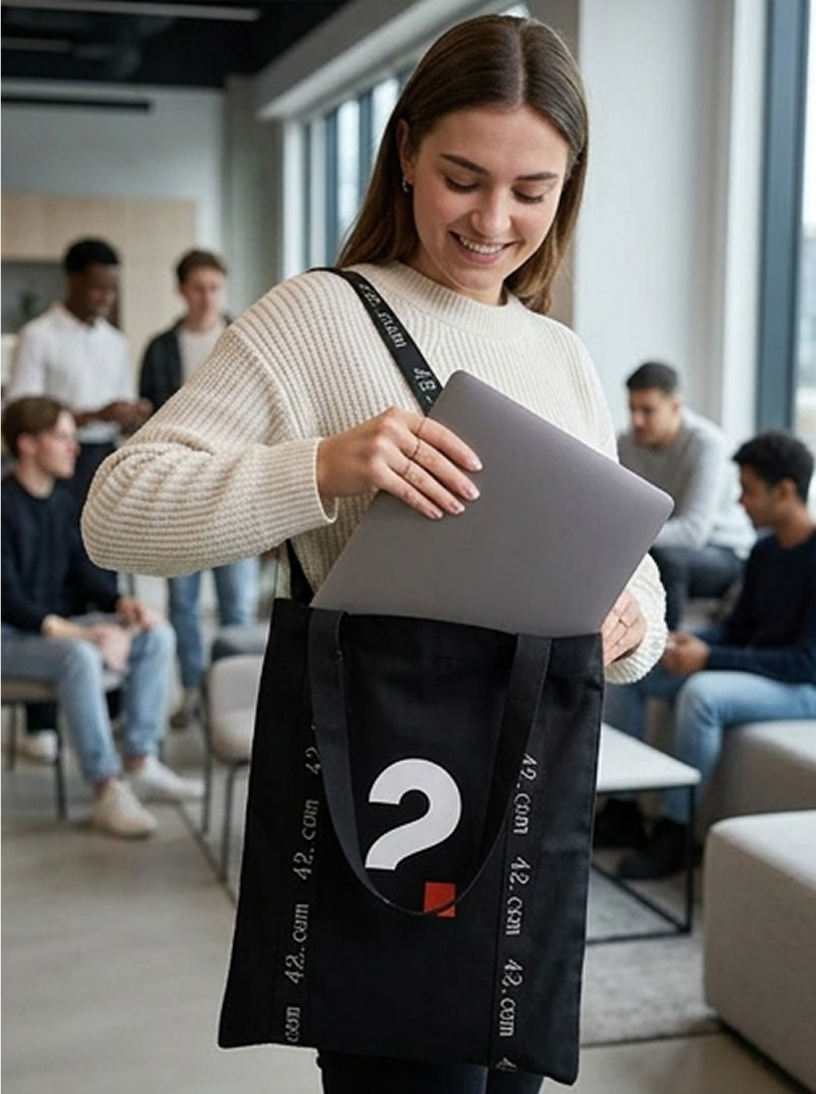 Pessoa guardando um notebook em sacola personalizada preta com logo 42